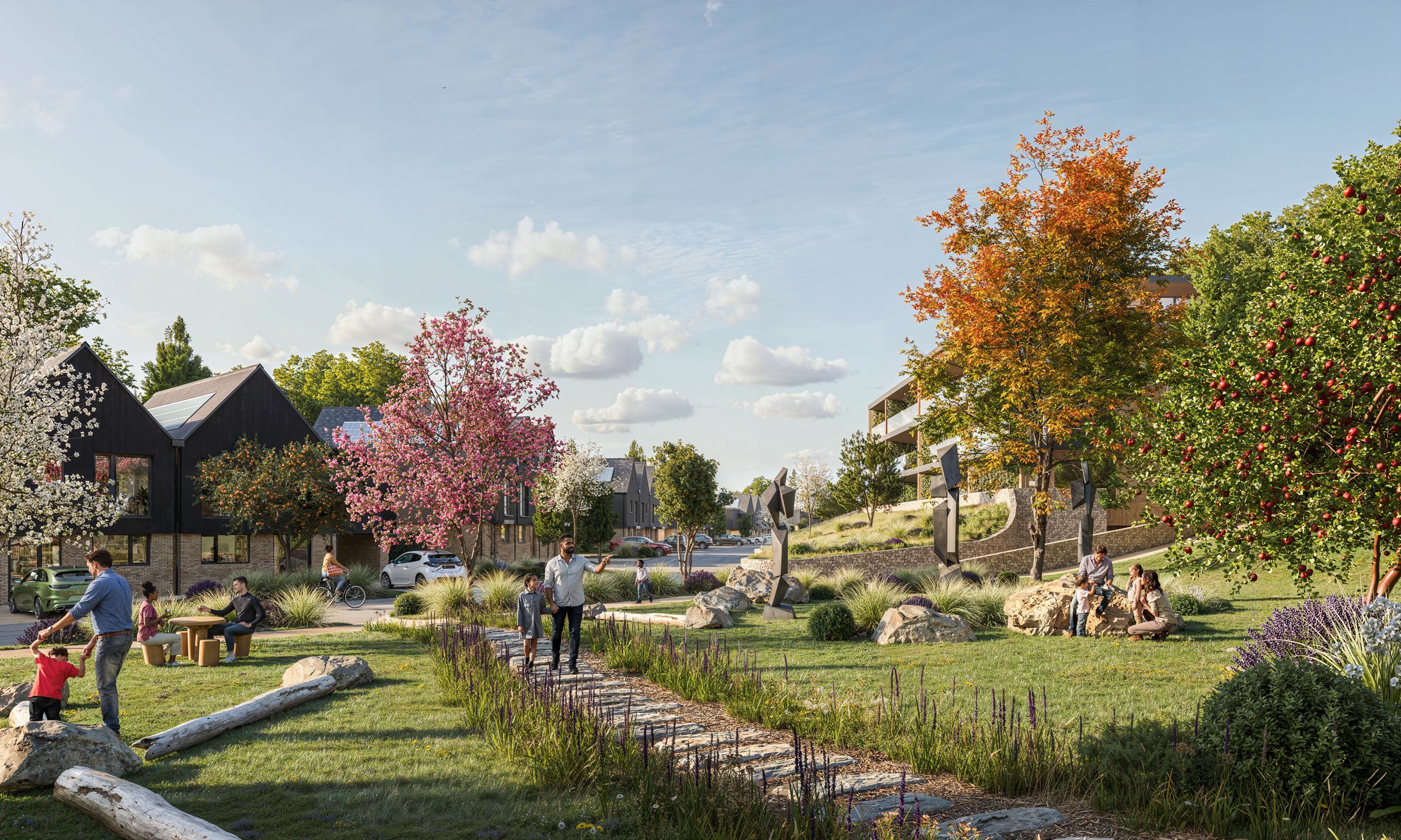 Families enjoying a planted glade at Coastal Glades, with dark-boarded gabled homes and apartments set among mature trees